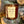 Load image into Gallery viewer, bonfire on the beach limited edition soy candle in amber tumbler by veil and dagger fine home goods sitting on firewood outside