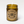 Load image into Gallery viewer, candle burning in amber glass apothecary jar with cotton wick on white background. Circle kraft paper label has crossed arrows and reads Calm Baby wooly beast soy wax candle handmade in portland oregon