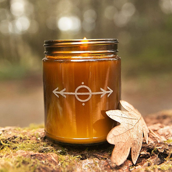 Woodsman 2 pine cedarwood leather scented engraved soy candle laser etched nordic design amber jar sitting on mossy log with oak leaf