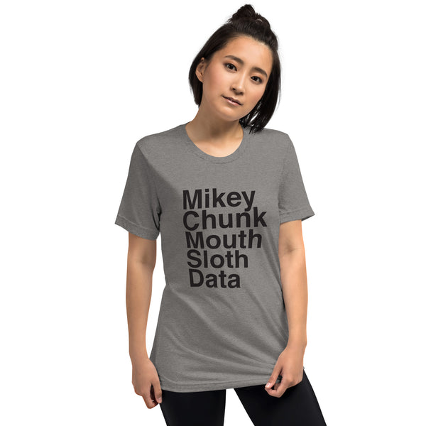 BIPOC girl with short black hair wearing heather grey goonies movie shirt and black pants against white background, shirt reads mikey chunk mouth sloth data