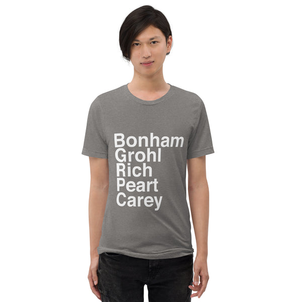 BIPOC male with black hair wearing Great Drummers T-shirt in grey on white background, shirt reads Bonham Grohl Rich Peart Carey