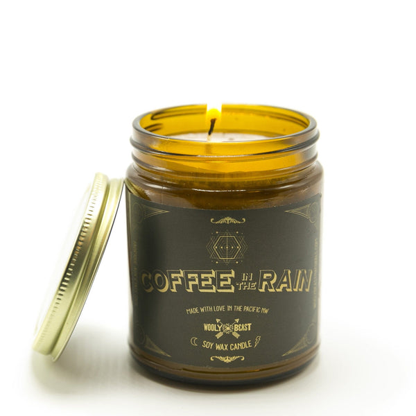 Coffee in the Rain Coffee Scented Soy Candle wick burning with lid leaning on white background by Wooly Beast Naturals